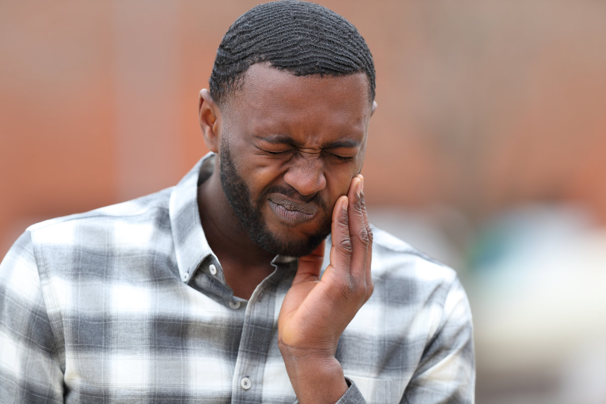 Front view portrait of a man with black skin complaining about tooth ache