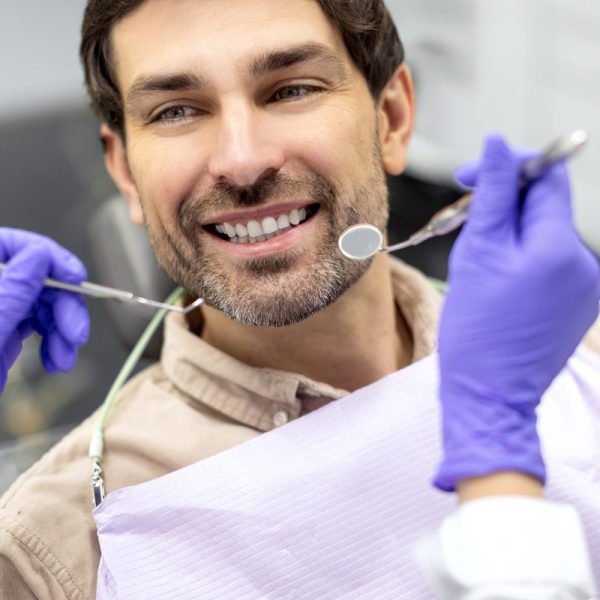 Closeup shot of dentist examining male patients teeth in dental clinic. Man having his teeth examined by female dentist